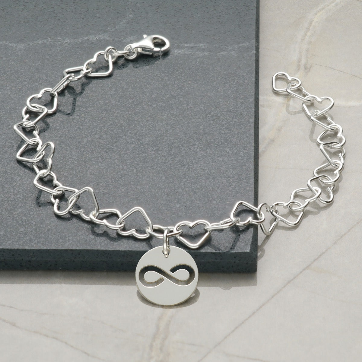 Sterling Silver Heart link anklet With attached round Charm featuring a cut out infinity symbol