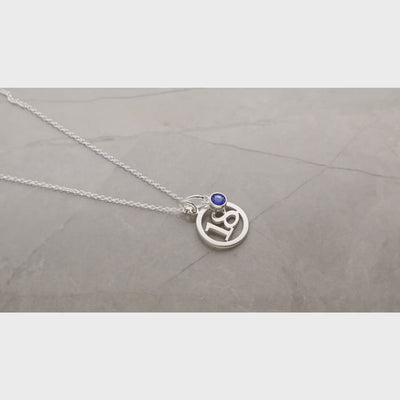 video of silver round number pendant necklace and biue birtstone charm viewed in a 180 degree sweep